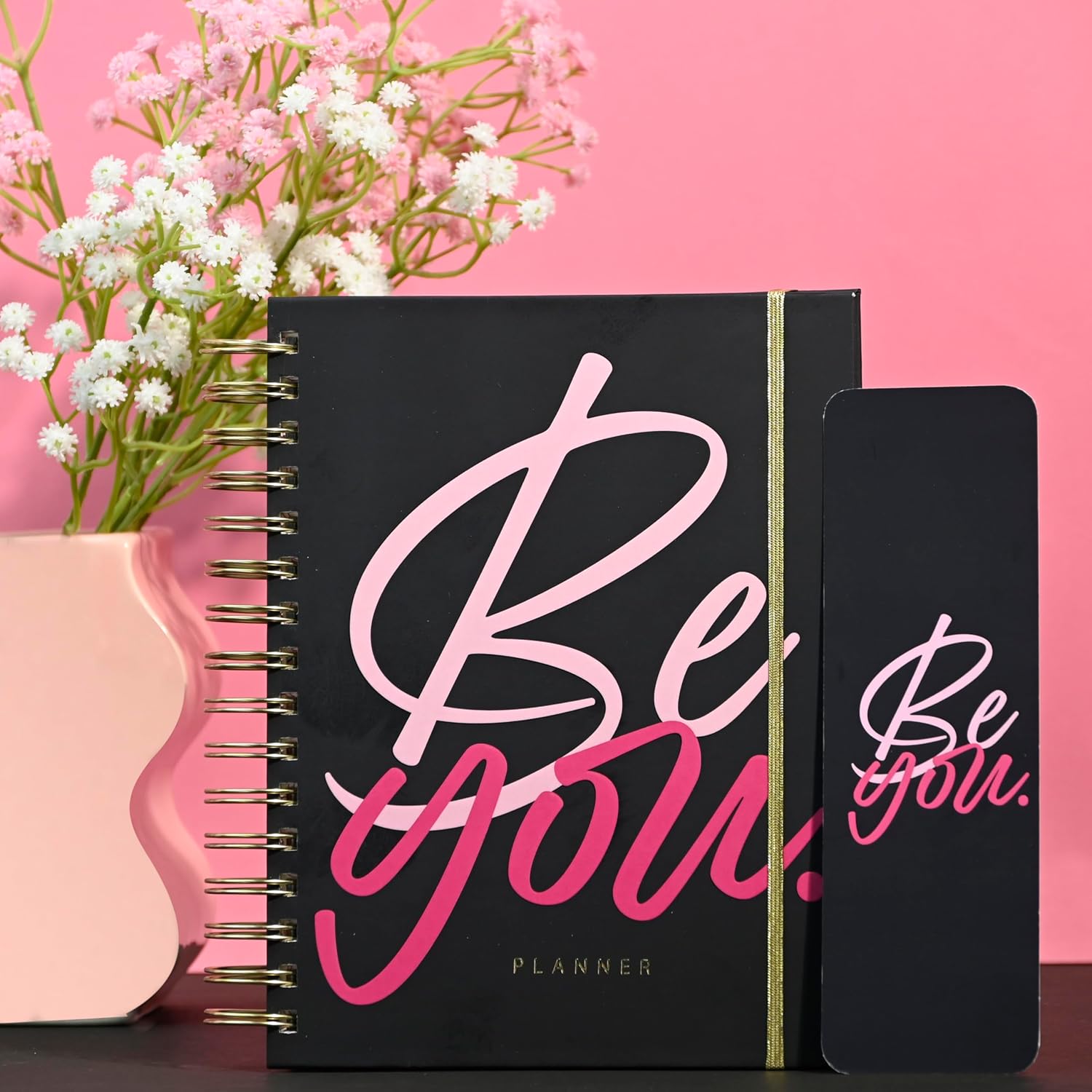 Black planner with 'Be you' text on a pink background with flowers