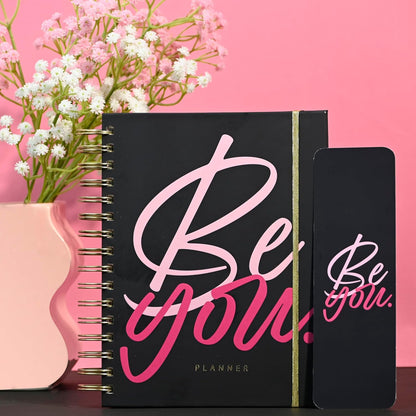 Black planner with 'Be you' text on a pink background with flowers