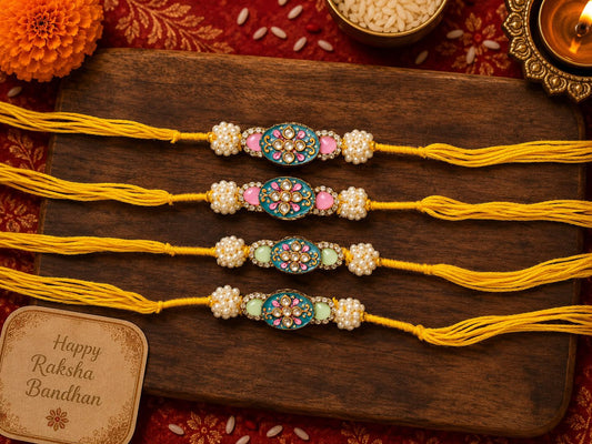 Four traditional Indian Rakhi wristlets arranged on a dark wooden board, featuring yellow cords, white pearl-like beads, and colorful central medallions in blue, pink, and green. A small card reading 'Happy Raksha Bandhan' is visible in the lower left, with festive decorative elements around the board.