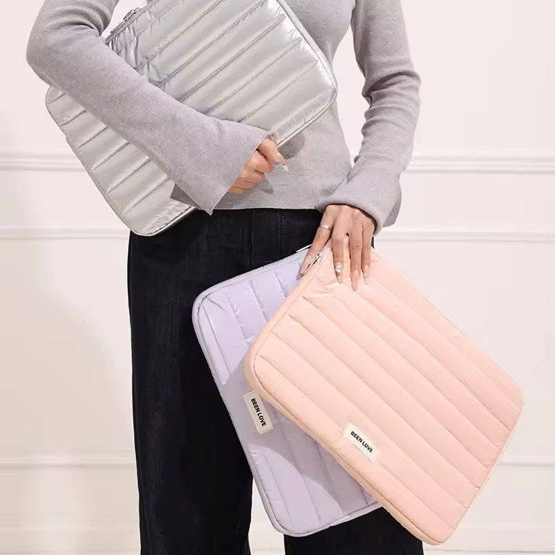 Person holding two inflatable travel cases, one white and one pink, against a light background.