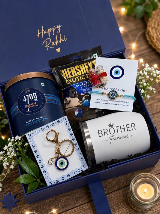 A blue gift box arranged on a wooden surface with warm string lights and flowers. The box contains a navy canister, a white insulated tumbler printed with 'BROTHER Forever', a keychain, a small card, and a chocolate bag.