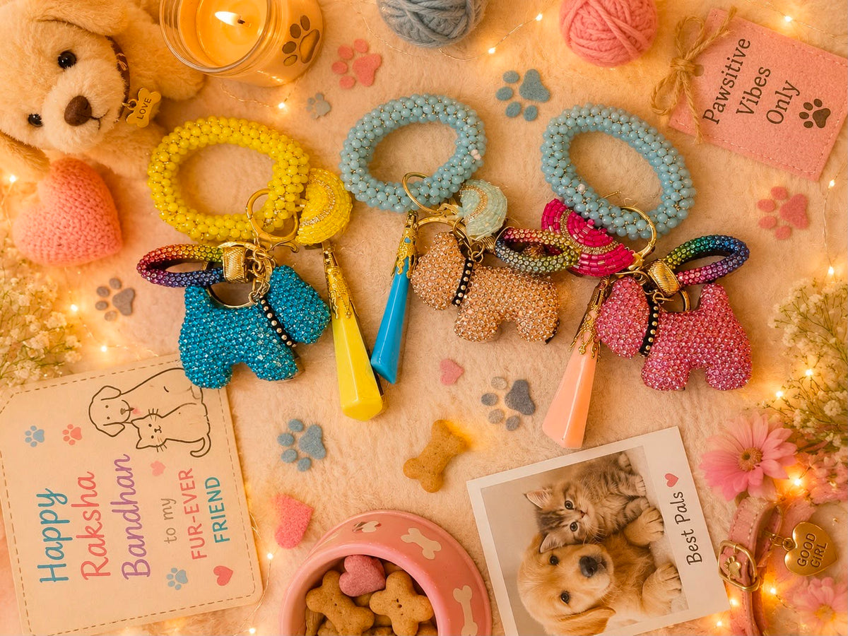 Three beaded dog-shaped keychains in yellow, light blue, and pink, arranged on a cozy beige fabric background with warm fairy lights, a teddy bear, and pet-themed cards and accessories.