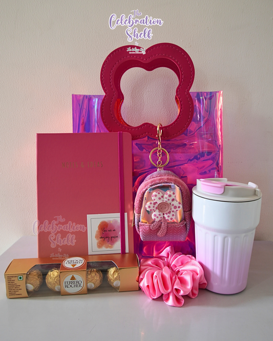 Collection of pink-themed items including a keychain, scrunchie, and tumbler on a white surface with 'The Celebration Shelf' branding.