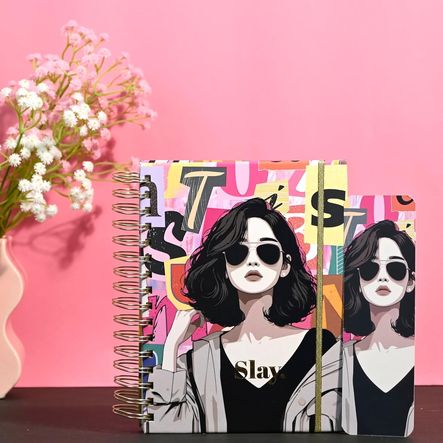 Notebook with colorful design featuring two women and the word 'Slay' on a pink background.