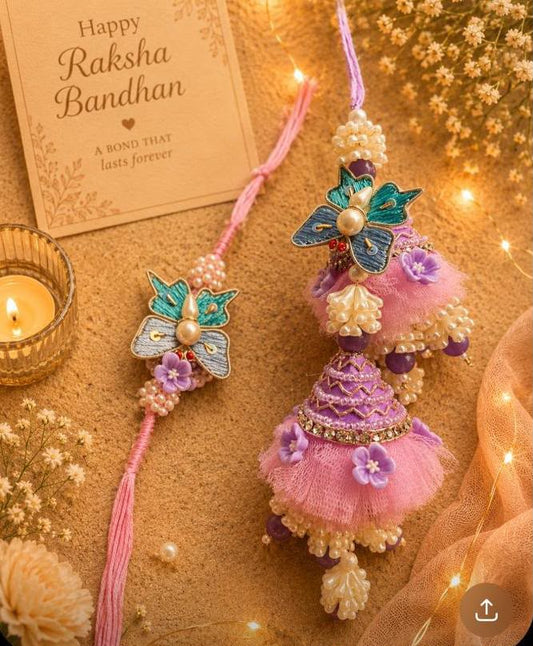 Two decorative Rakhi bracelets displayed on a warm beige surface with a lit candle, dried flowers, and fairy lights. One Rakhi has a pink tassel and a blue-green butterfly charm with pearl beads.