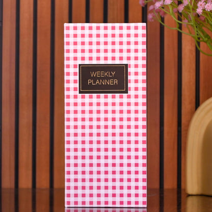 Weekly planner with pink checkered design on a wooden surface