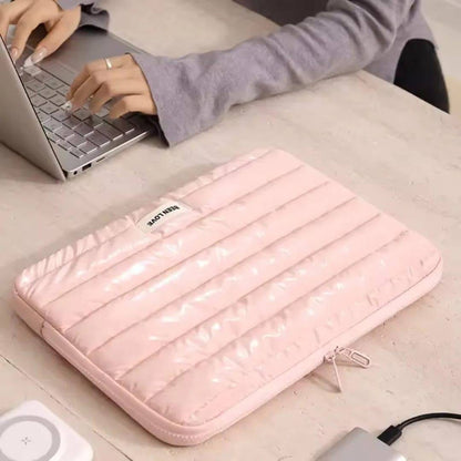 Pink laptop case on a desk with a person using a laptop in the background