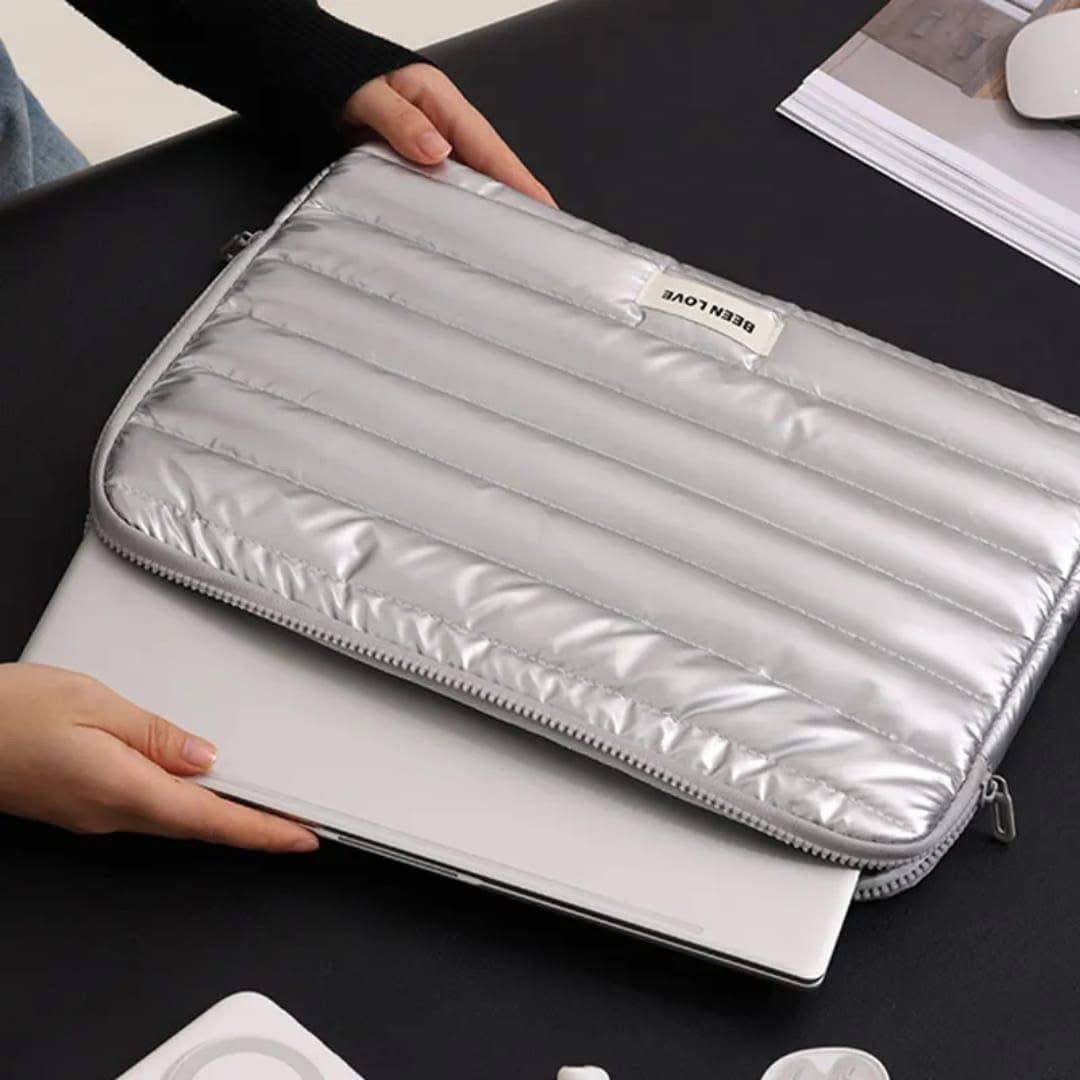 Silver laptop sleeve held by a person on a dark surface